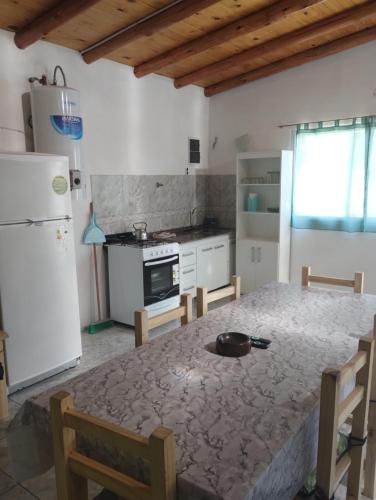a kitchen with a table and a white refrigerator at Atardecer Serrano in Huerta Grande