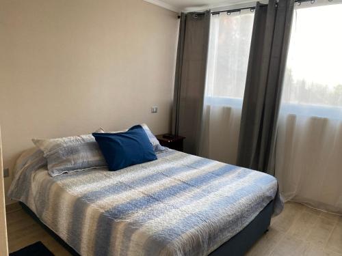 Un dormitorio con una cama con una almohada azul. en Departamento en Viña del Mar, en Viña del Mar