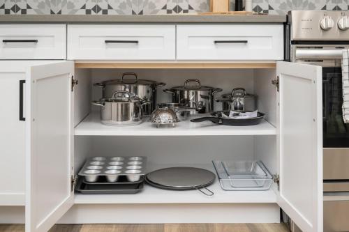 a kitchen with white cabinets with pots and pans at Updated 2BR 1BA Flat Steps from 25th Street Fun in Ogden