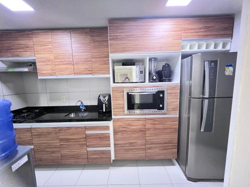 cocina con armarios de madera y nevera de acero inoxidable en Apartamento vista ao mar en São Luís