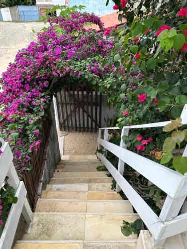 a garden with pink flowers and a white fence at Mar de Gente Pousada in Praia de Moitas
