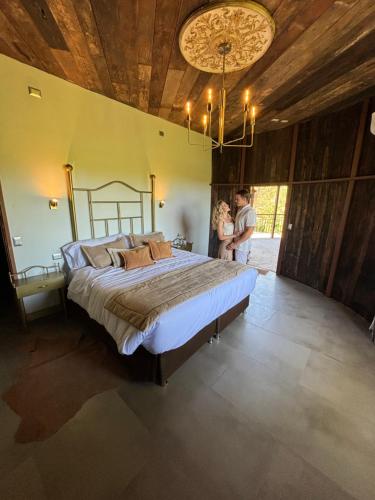 a couple standing in a bedroom with a large bed at Cava Colchagua Hotel Boutique in Santa Cruz