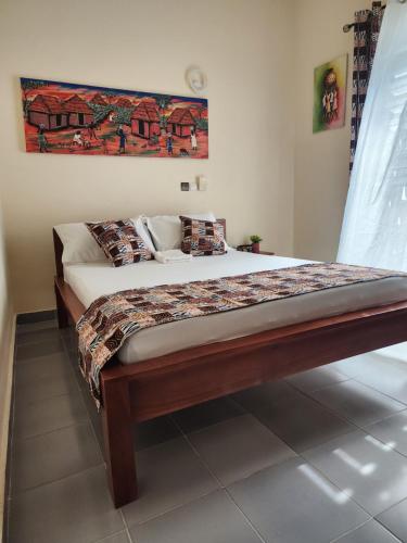 a large bed in a bedroom with a large painting on the wall at Home away from Home in Cococodji