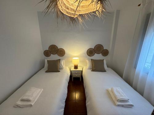 - 2 lits jumeaux dans une chambre avec une lampe et une fenêtre dans l'établissement Villa en Frigiliana con piscina, jacuzzi y espectaculares vistas, à Frigiliana