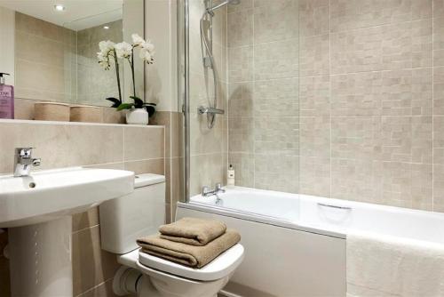 a bathroom with a toilet and a sink and a tub at Elegant Double Room with private bathroom in Central Reading in Reading