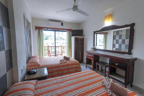 1 dormitorio con 2 camas, espejo y escritorio en Hotel y Villas Quinta Minas, en Los Ayala