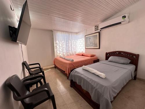 a bedroom with two beds and a flat screen tv at Casa Los Almendros, Valledupar casa completa in Valledupar