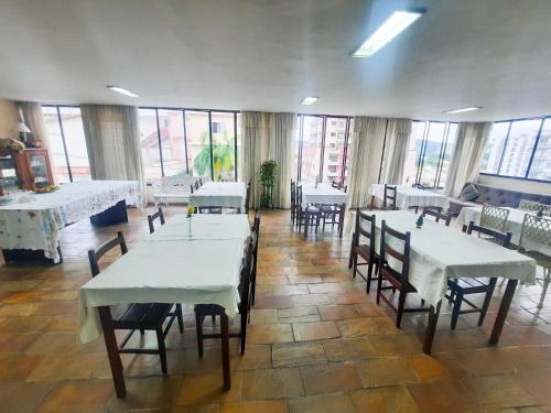 a restaurant with white tables and chairs and windows at Hotel Pousada das Rosas in São Lourenço
