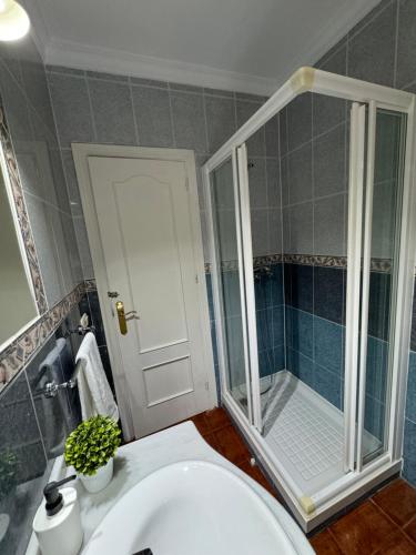 La salle de bains est pourvue d'une douche et d'un lavabo blanc. dans l'établissement Villa en Frigiliana con piscina, jacuzzi y espectaculares vistas, à Frigiliana