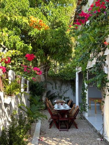 a table and chairs in a garden with flowers at Mar de Gente Pousada in Praia de Moitas