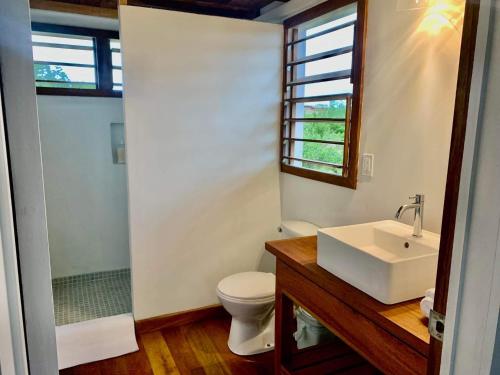 a bathroom with a sink and a toilet and a window at Belizima Eco Resort in Sarteneja