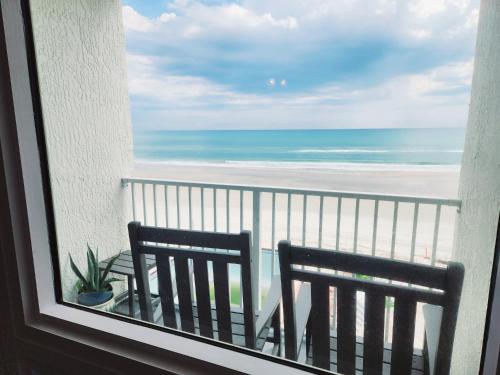 a view of the beach from a balcony with two chairs at Purple Reign: A Chic, Romantic Oceanfront Getaway - Sleeps 4 in Daytona Beach