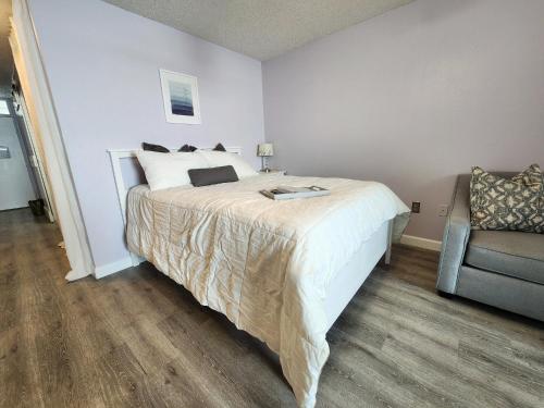 a bedroom with a large bed and a chair at Purple Reign: A Chic, Romantic Oceanfront Getaway - Sleeps 4 in Daytona Beach