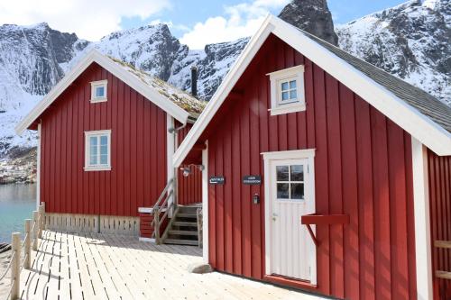a red building with snow covered mountains in the background at Valen Cabins in Reine in Reine