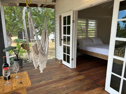 a room with a bed and a hammock on a porch at Belizima Eco Resort in Sarteneja