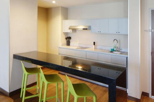 a kitchen with a counter with three green chairs at City Express Suites by Marriott Tijuana Rio in Tijuana