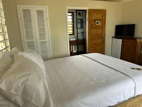 a bedroom with a white bed and a television at Belizima Eco Resort in Sarteneja