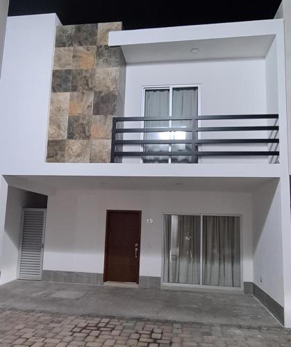 Cette maison blanche dispose d'un balcon et d'une porte. dans l'établissement Privada del Mar Altata, à Altata