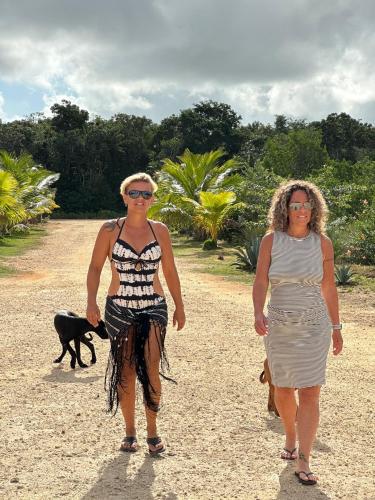 two women walking down a dirt road with a dog at Belizima Eco Resort in Sarteneja