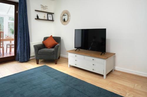 a living room with a flat screen tv and a chair at Entire House in Cambridge in Cambridge