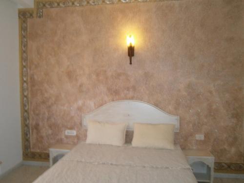 ein Schlafzimmer mit einem Bett mit einer Lampe an der Wand in der Unterkunft Tataouineranch in Tataouine