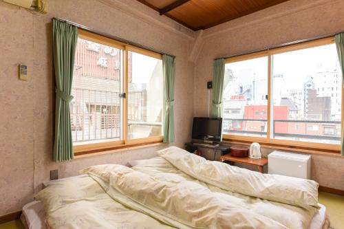 um quarto com uma cama e 2 janelas grandes em Ryokan Mikawaya em Tóquio
