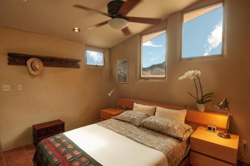 a bedroom with a bed and two windows at Galeria Viviente Eco Casita in Bisbee
