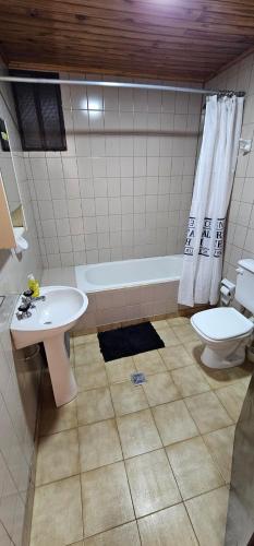 a bathroom with a sink and a toilet and a tub at Matices Hostel Centro in El Calafate