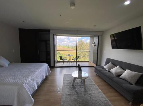 1 dormitorio con cama, sofá y mesa en Suite Llanogrande, en Rionegro