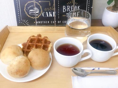 a table with a plate of waffles and two cups of coffee at Hotel Yudanaka in Yamanouchi