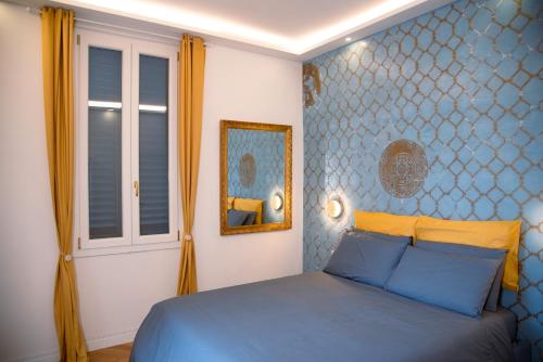 Dormitorio azul con cama y espejo en Casa Michelazzi Apartment Careggi / Dalmazia, en Florencia