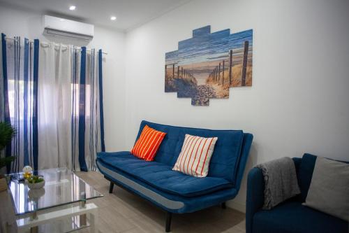 a living room with a blue couch and a painting at Just4uApartment - Near Lisbon & Beach - With AC in Almada