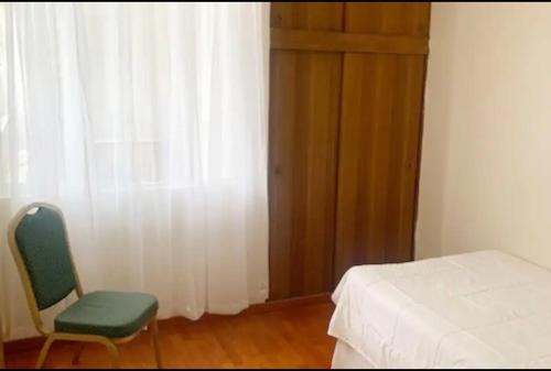 ein Schlafzimmer mit einem Bett, einem Stuhl und einem Fenster in der Unterkunft DEPARTAMENTO PISO 2 FRENTE AL MAR in Antofagasta