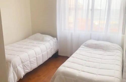 1 Schlafzimmer mit 2 Betten und einem Fenster mit weißer Bettwäsche in der Unterkunft DEPARTAMENTO PISO 2 FRENTE AL MAR in Antofagasta