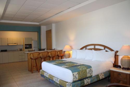 a bedroom with a large bed and a kitchen at Fajardo Inn Resort in Fajardo