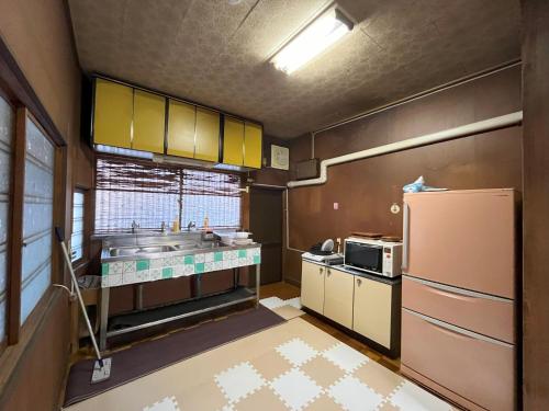 cocina con armarios amarillos y nevera en 福井駅から徒歩2分の1棟貸切民泊 最低限 en Fukui