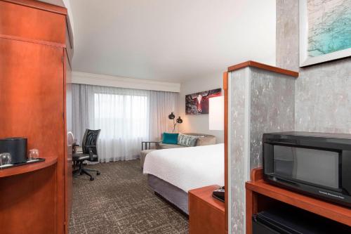 a hotel room with a bed and a tv at Courtyard by Marriott San Antonio North Stone Oak At Legacy in San Antonio