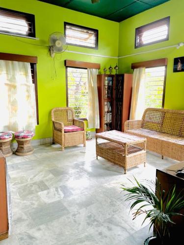 uma sala de estar com paredes verdes e móveis de vime em Namdang Homestay em Sibsāgar