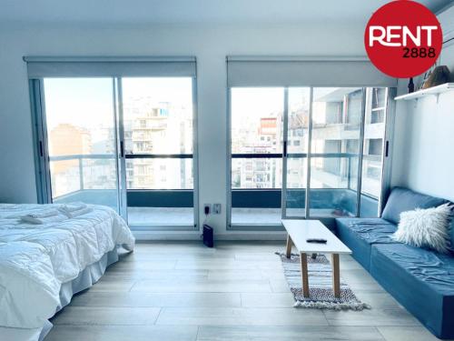 1 dormitorio con cama, sofá y ventanas en Rent Juan B Justo en Buenos Aires