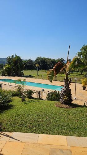 a swimming pool in a park with a palm tree at Sítio Santa Cecília in Itapetininga