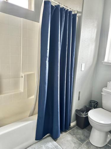 a bathroom with a blue shower curtain and a toilet at Fantastic Bright 4 Bedroom- Deck - Fireplaces in Medford