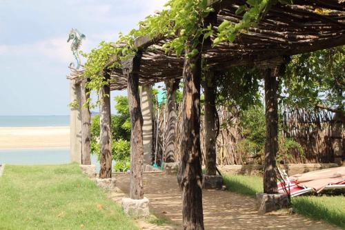a wooden pergola with trees on a beach at C Beyond Nilaveli in Nilaveli