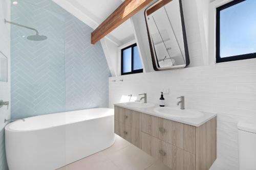 La salle de bains blanche est pourvue de 2 lavabos, d'une baignoire et d'une baignoire. dans l'établissement 5BR Mermaid Waters Luxury Home, à Gold Coast