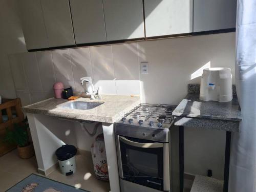 a small kitchen with a stove and a sink at Apt C com 2 quarto com ar e garagem in Montes Claros