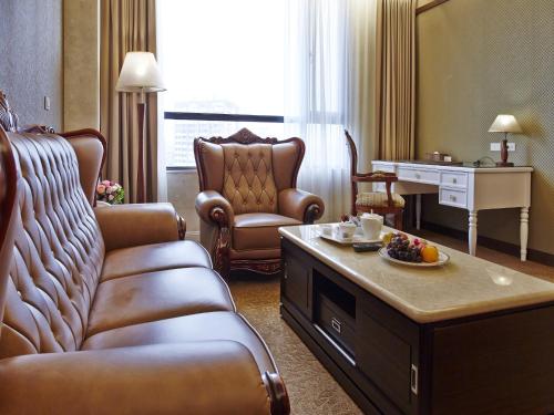 a living room with a couch and chairs in a hotel room at Royal Chiayi Hotel in Chiayi City