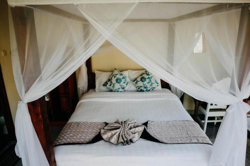 a bedroom with a canopy bed with pillows at Padi Bali Jatiluwih in Tabanan