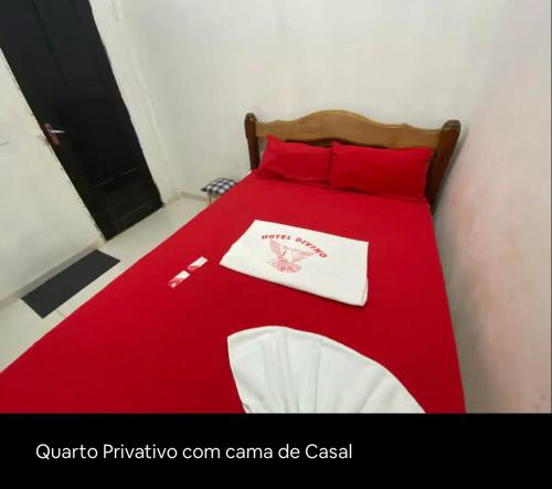 Una cama roja con una manta roja encima. en Hotel Divino, en Caissara