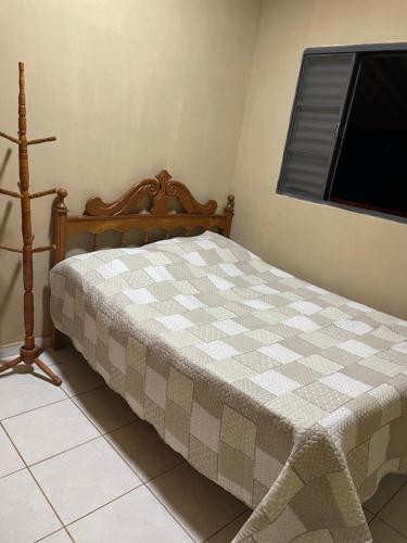 een slaapkamer met een bed met een geruite deken bij Casa para temporada, Guilherme. in Vargem Bonita