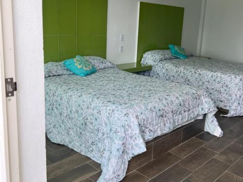 two beds in a room with green walls at Hotel El Mirador y Jardin in Tlayacapan