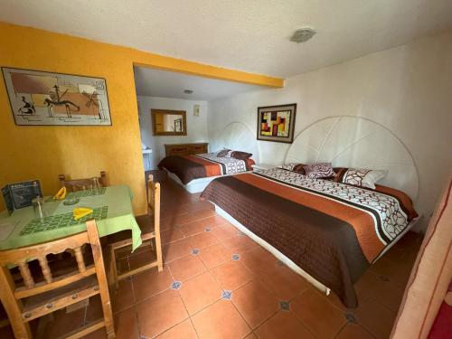 a hotel room with two beds and a table at Hotel El Mirador y Jardin in Tlayacapan